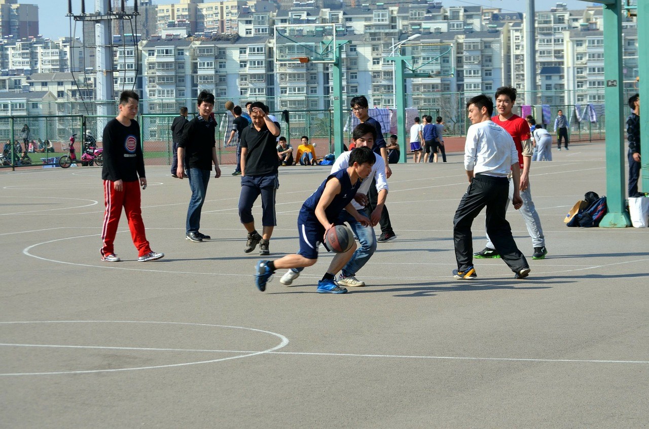 A group of teenagers playing basketball on a court in the middle of a city