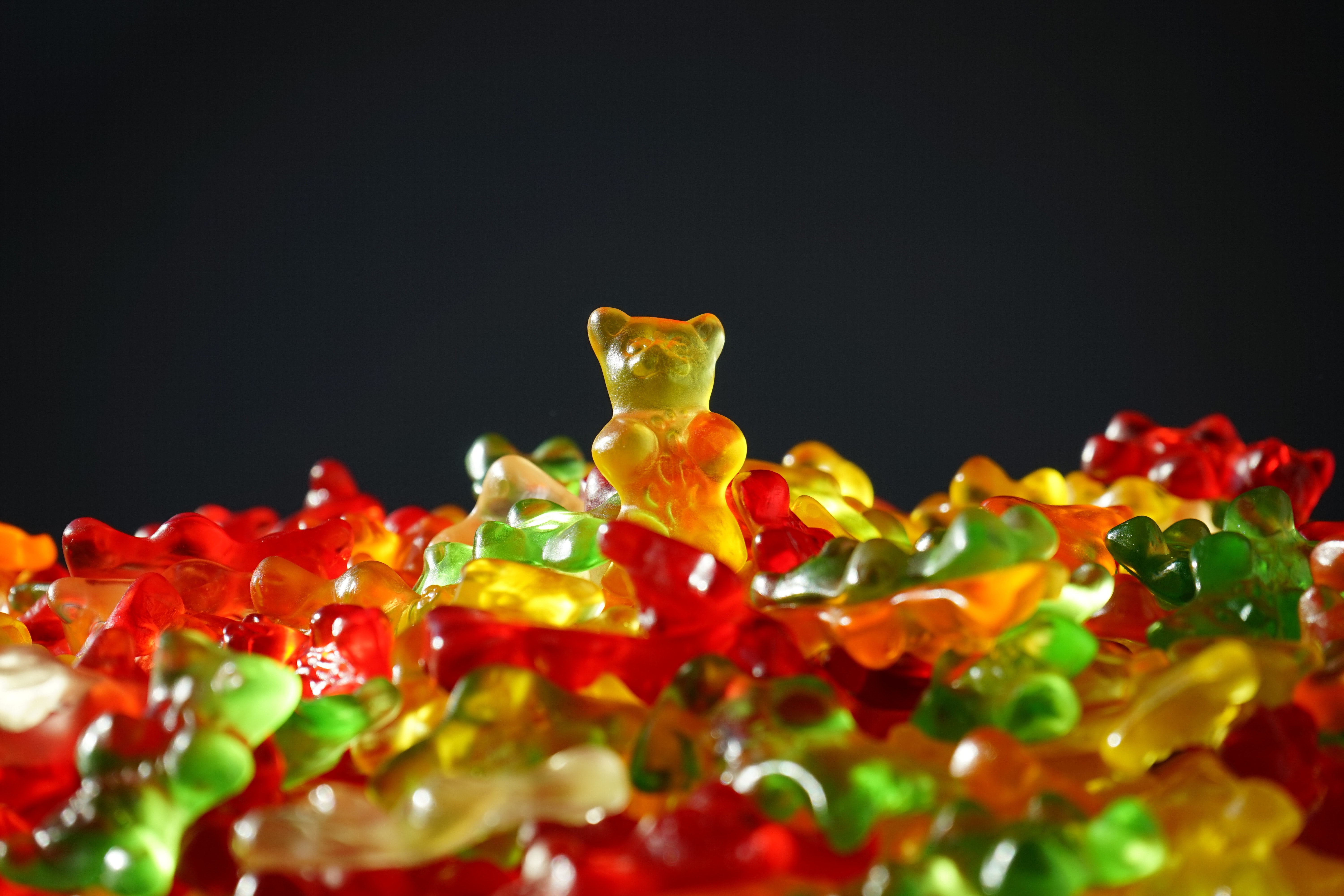Green, yellow, and orange gummy bear candies in a cute pile.