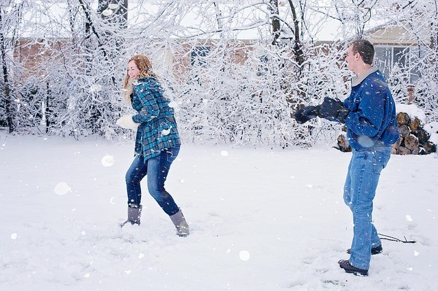 Snowball fight! A couple hurls snowballs at each other on a snowy day