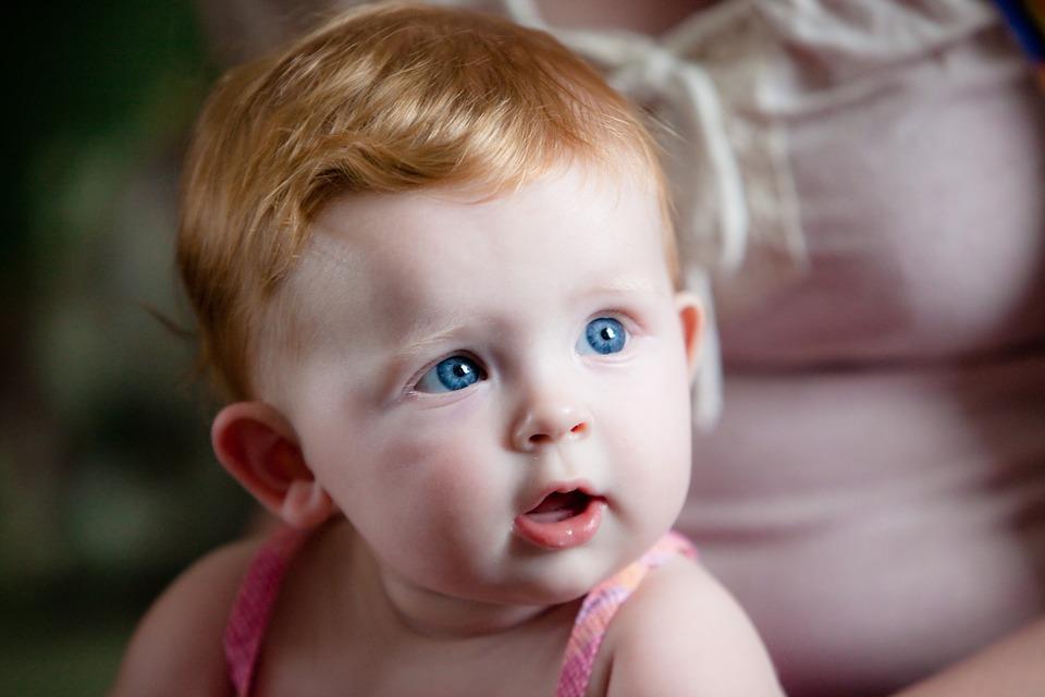A baby girl with brunette hair and blue eyes
