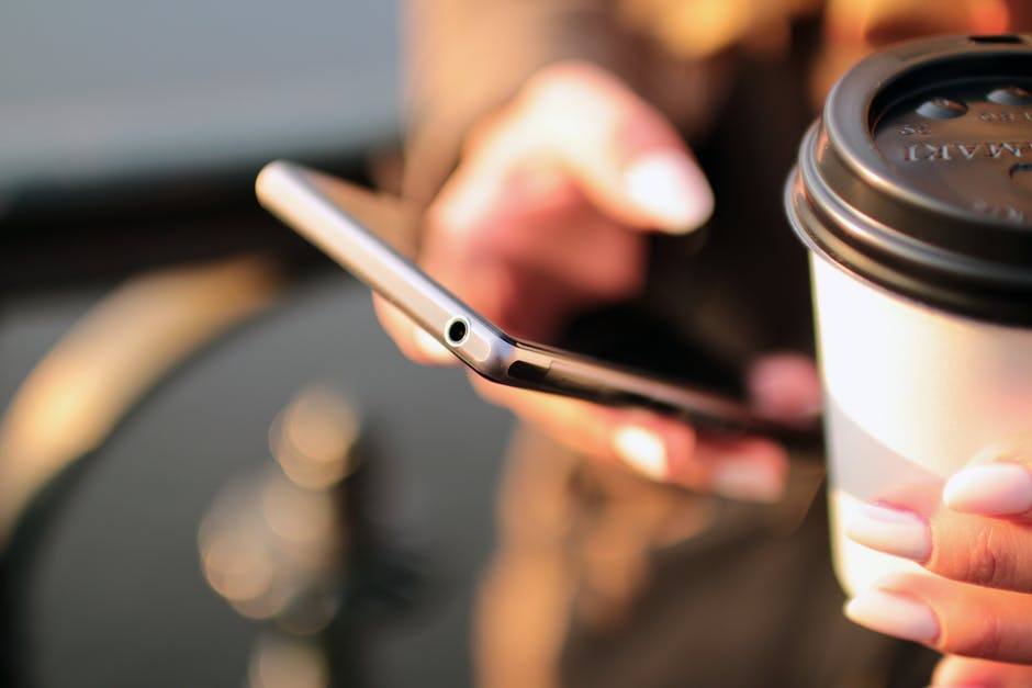 Picture of a phone in someone's hand with a blurred background, so as to make the phone the primary target of the picture.
