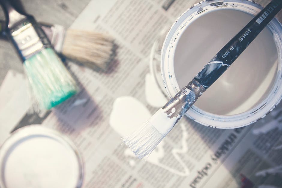 White paint, buckets of paint, and newspaper