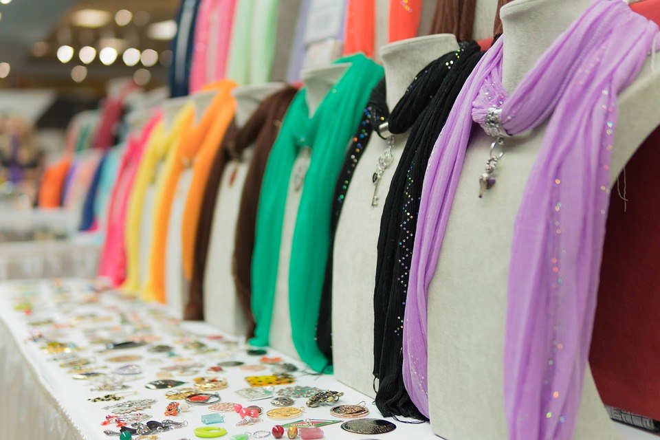 An array of colorful scarfs on mannequins, each one having a piece of matching jewelry.