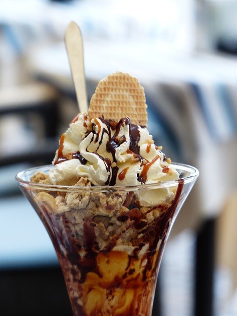 An ice cream sundae with chocolate and caramel sauces, along with nuts swirled around in vanilla ice cream