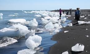 Ice on a beach with people.