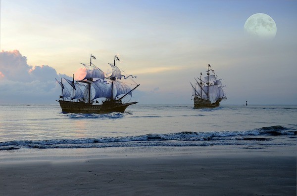 Two ships at sea in the moonlight.