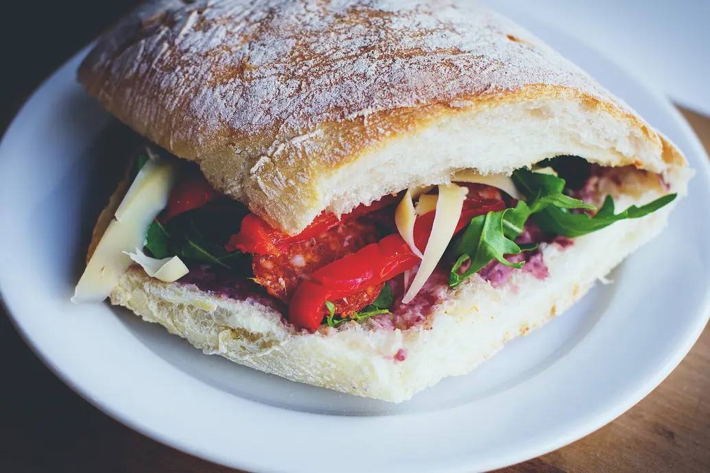 A sandwich with brie, tomatoes, arugula, and jelly on ciabatta. Yum!