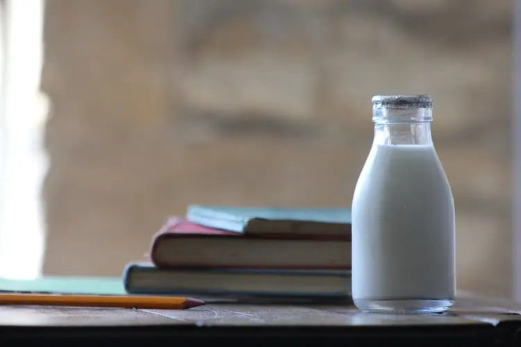 Image description: Bottle of milk next to books and pencil