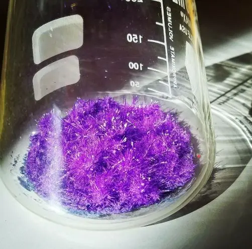 Image description: Flask with purple chemical with crystal branches.