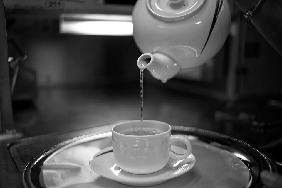 Image of hot water being poured out of a teapot into a cup.